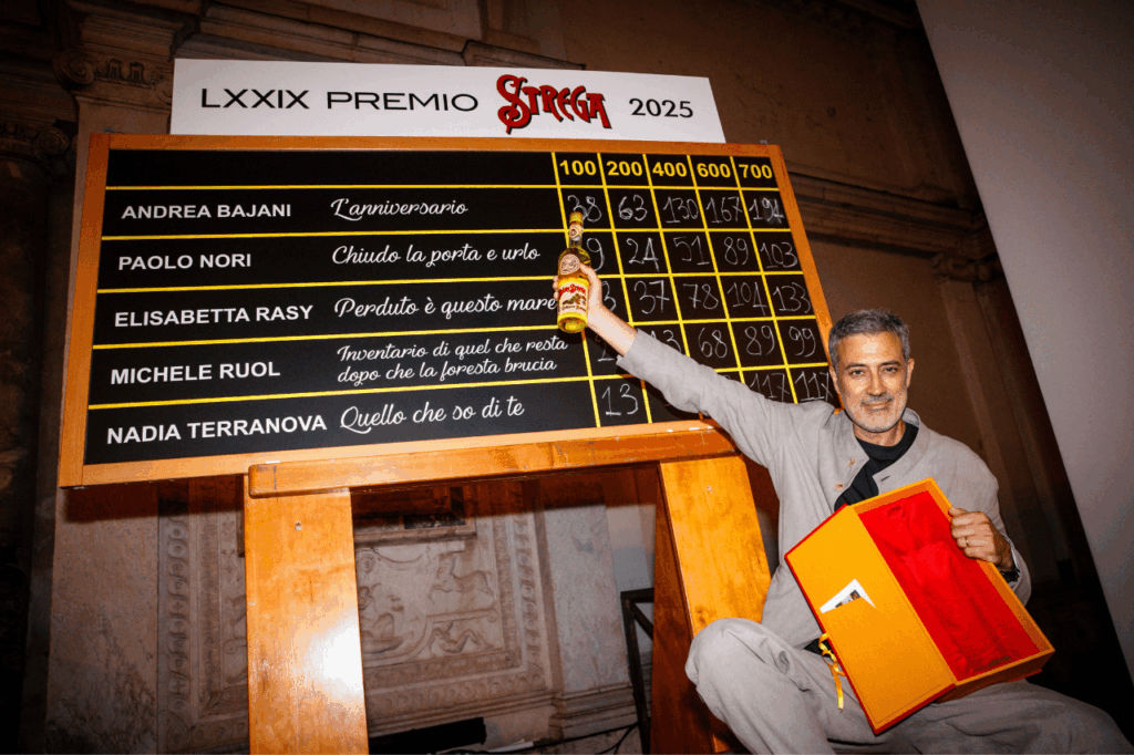 Andrea Bajani in posa davanti alla lavagnetta del premio Strega 2025
